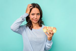 Frau, die Eier in den Händen hält und irritiert schaut